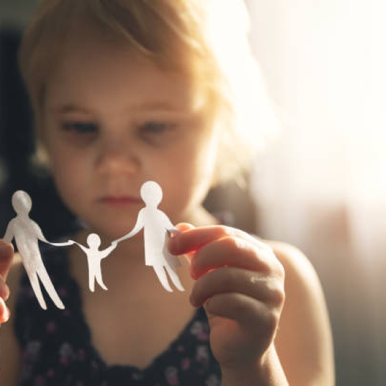Billede af en lille pige, der holder et papirklip af en mor en far og et barn