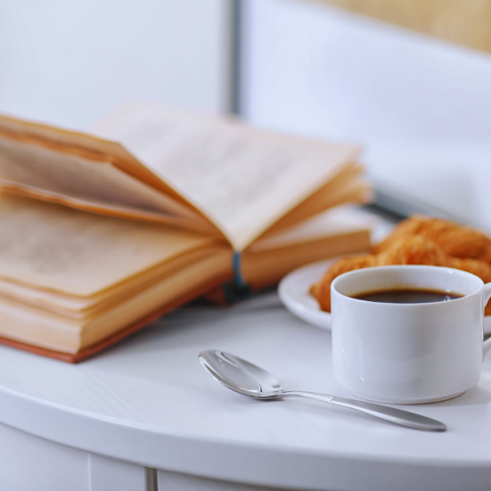 En åben bog, en kop kaffe og morgenbrød