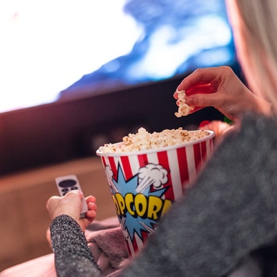 Pige spiser popcorn foran tv