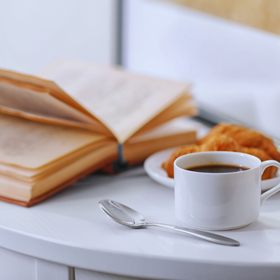 En åben bog, en kop kaffe og morgenbrød