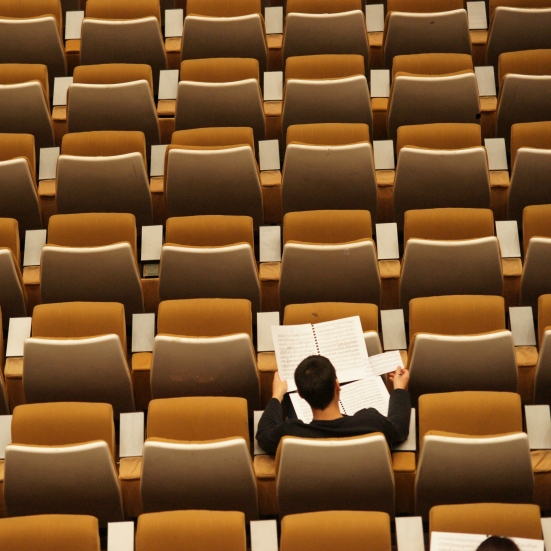 Studerende der sidder og læser i en tom foredragssal