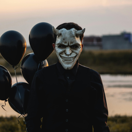 Mand med djævlemaske og sorte balloner.