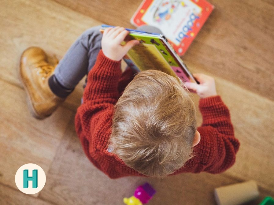 Et barn med bøger set fra oven